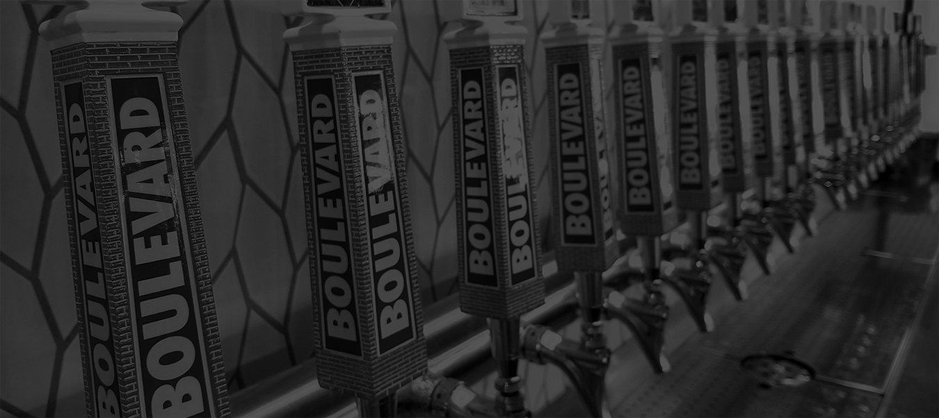 A row of beer taps labeled "Boulevard," lined up against a tiled wall. The black and white image highlights the uniformity and branding of the taps in a bar setting.