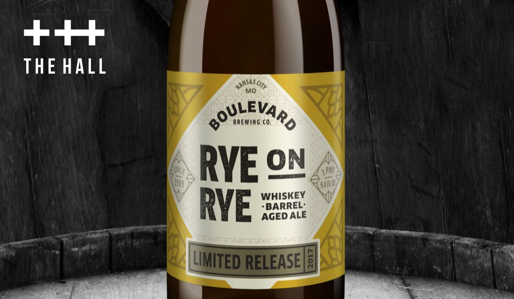 A bottle of Boulevard Brewing Co.'s "Rye on Rye" whiskey barrel-aged ale is centered. The label features gold and black design elements. "Limited Release 2017" is noted on the label. Background includes a rustic wooden texture and "The Hall" logo.