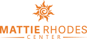 The Mattie Rhodes Center logo prominently features an orange stylized sun design above the center's name in bold orange letters, symbolizing warmth and community. Learn more about what we do and how this emblem reflects our mission to empower and uplift.